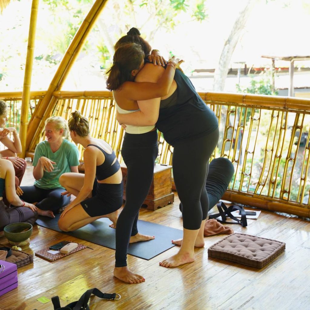 Students sharing a hug in the bamboo yoga shala at Power of Now Oasis in Sanur Bali