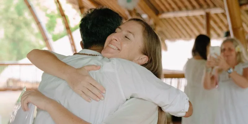 Yoga Teacher Training graduate hugging a teacher with a joyful smile during the graduation ceremony at the bamboo shala in Sanur, Bali