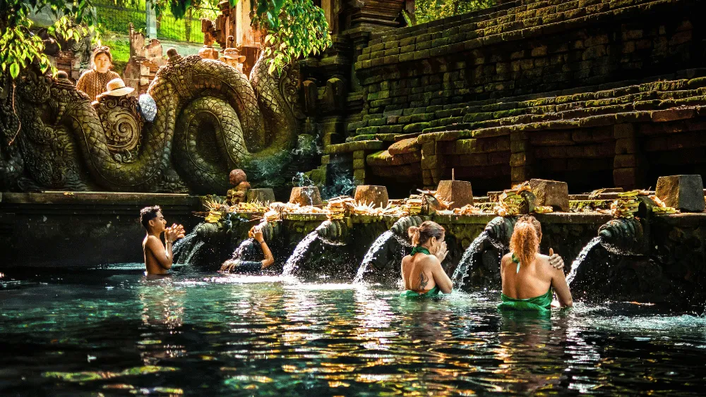 Visitors participating in a traditional water purification ritual at Pura Tirta Empul, a sacred Hindu temple in Bali known for its holy spring water.