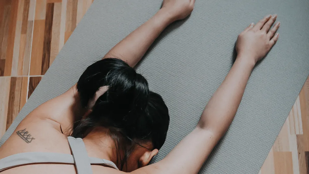 Woman practicing Extended Child’s Pose on a yoga mat during a Yin Yoga session