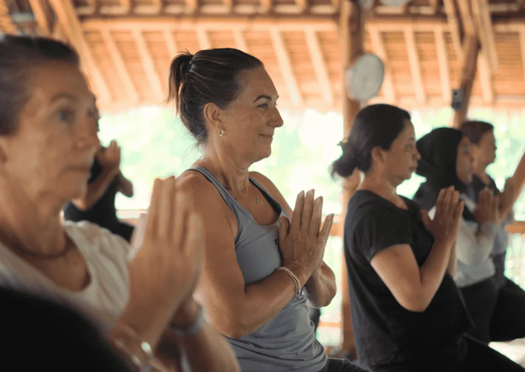Group of women practicing yoga in the bamboo shala at Power of Now Oasis in Sanur, Bali
