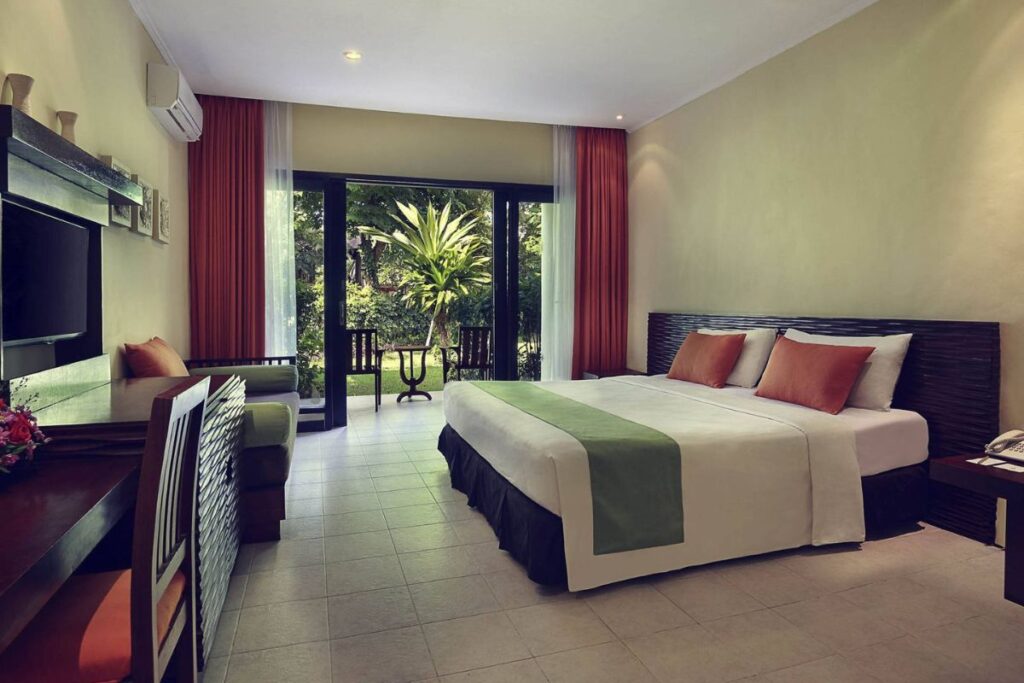 Spacious deluxe room with king-size bed, garden view, and modern amenities at Mercure Sanur Resort