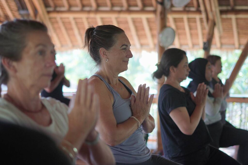 Retreat participants practicing yoga together in a bamboo shala.