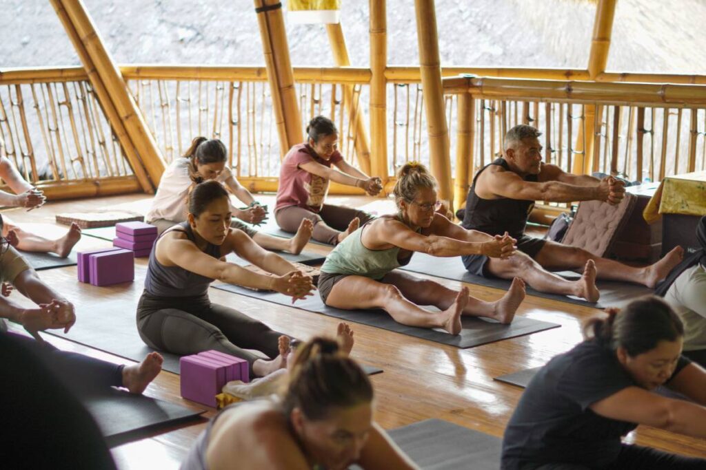 Retreat participants practicing a seated forward fold in the bamboo shala.