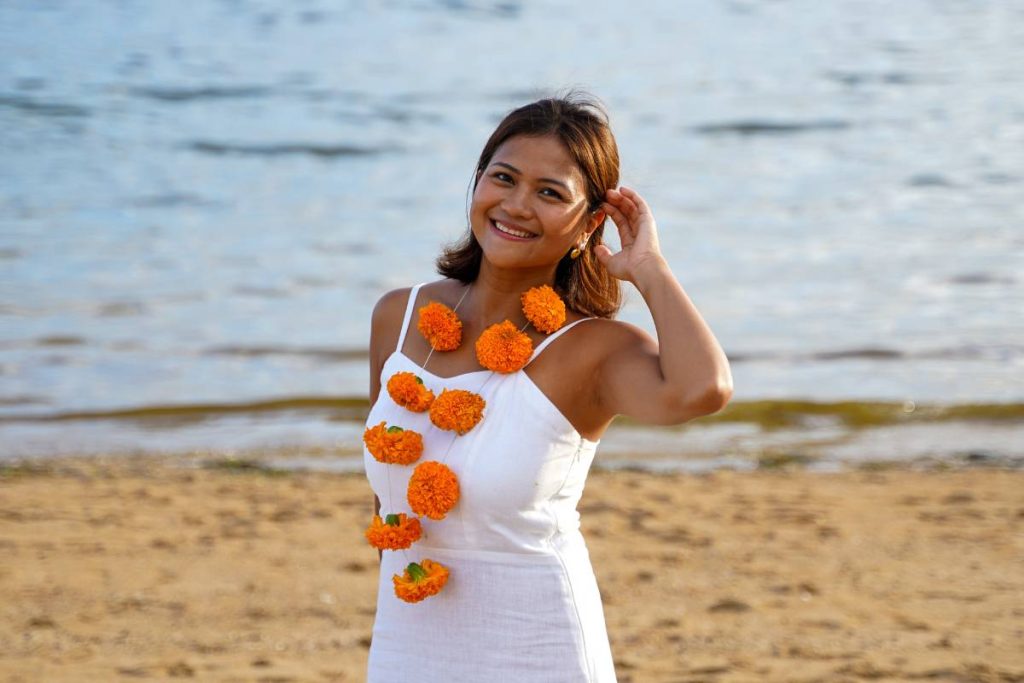 Allysa Yoga Teacher Portrait Power of Now Oasis Bali, yoga teacher at Power of Now Oasis, smiling on the beach in Sanur, Bali, wearing a marigold garland