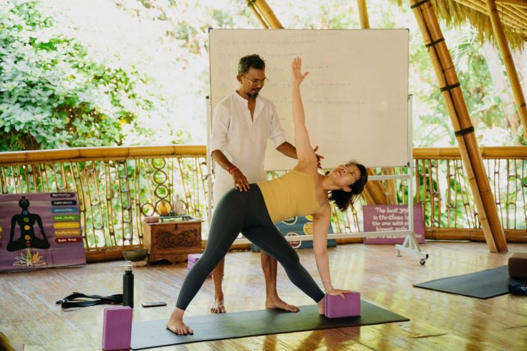 Krisna assisting a student in triangle pose during an alignment class at Power of Now Oasis Yoga Teacher Training, Bali